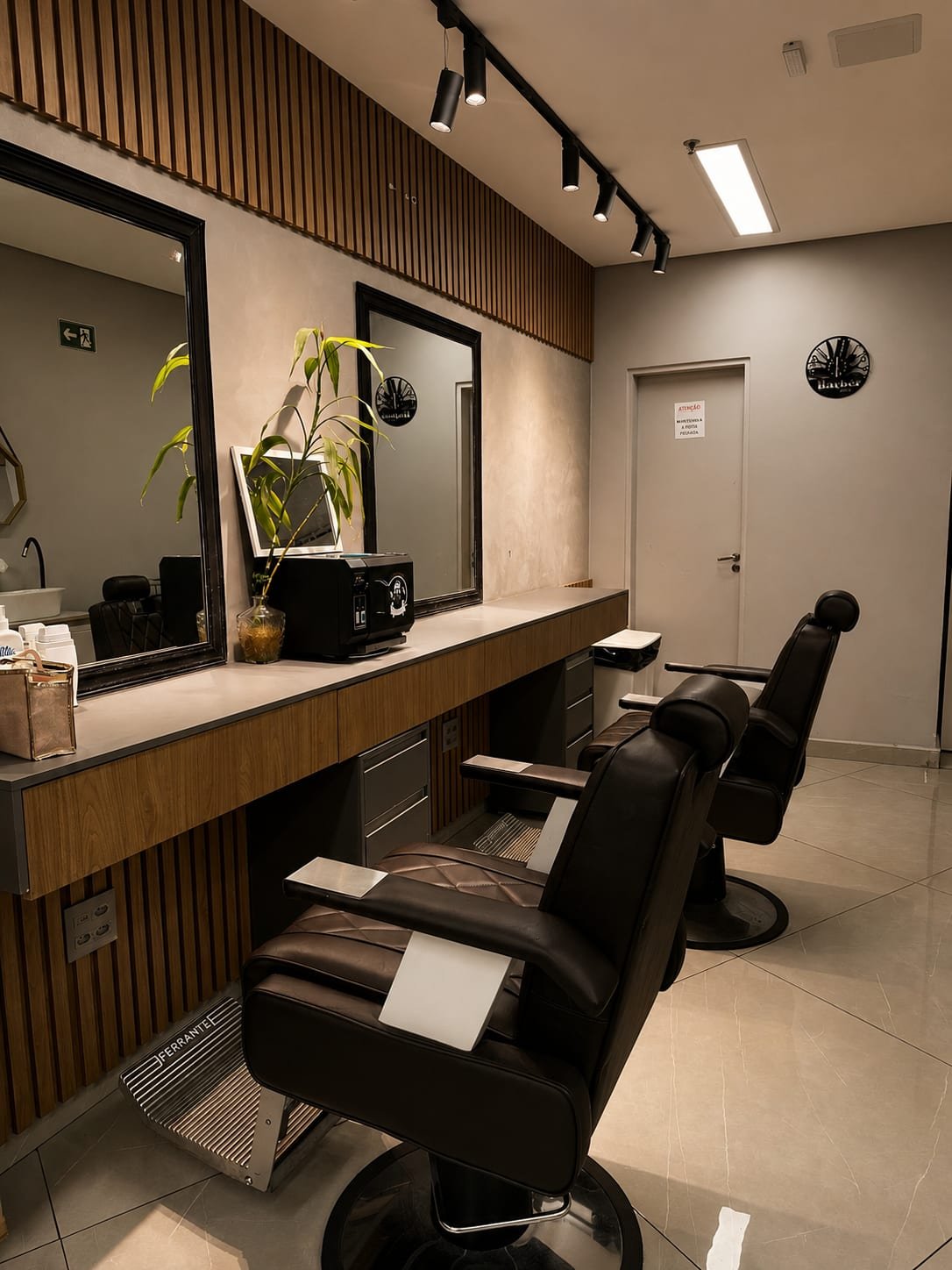 Cadeiras de barbearia em couro escuro com espelhos emoldurados